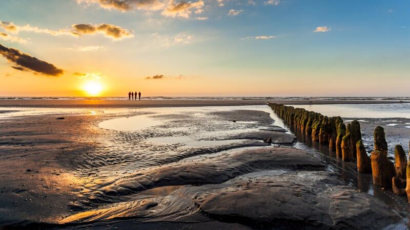 Sunset over mudflat with hiking group on the horizon. © Janis Meyer/Waddenagenda.