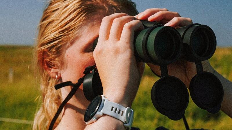 Young woman looking through binoculars. Katharina Greitemann.